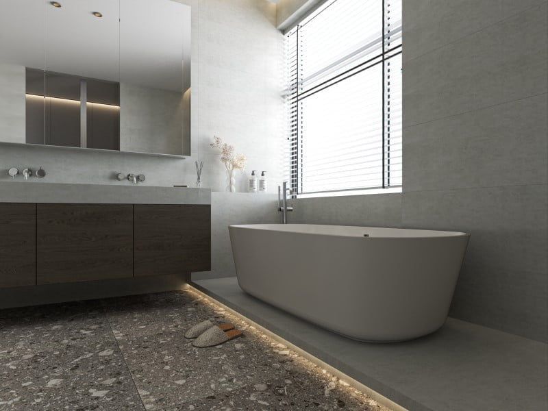 Nhà vệ sinh với nền tối và tường màu sáng, sử dụng gạch terrazzo hạt lớn, tạo nên phong cách đơn giản và tinh tế.